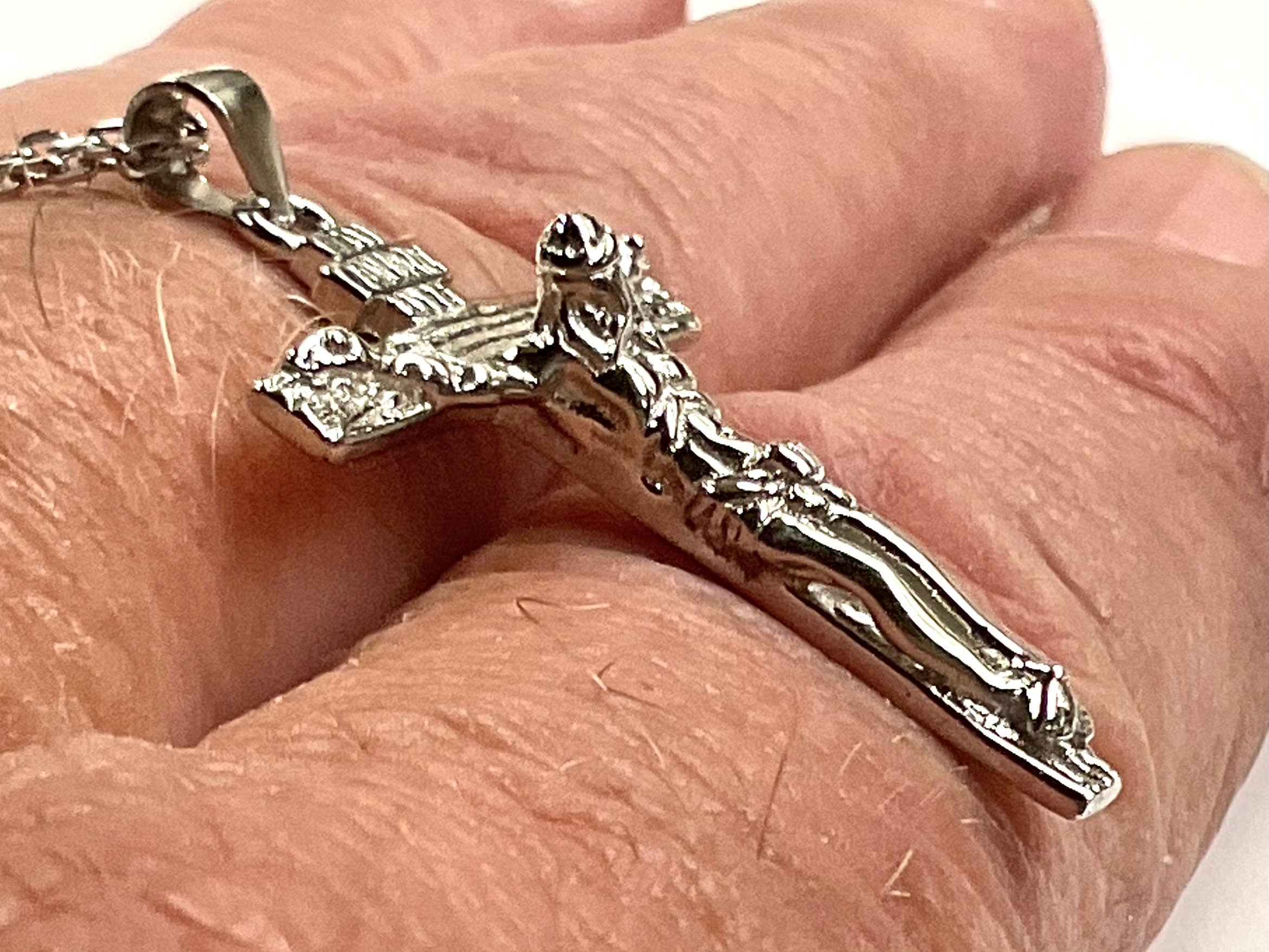 Close-up of silver crucifix pendant with gold-toned Jesus figure on chain