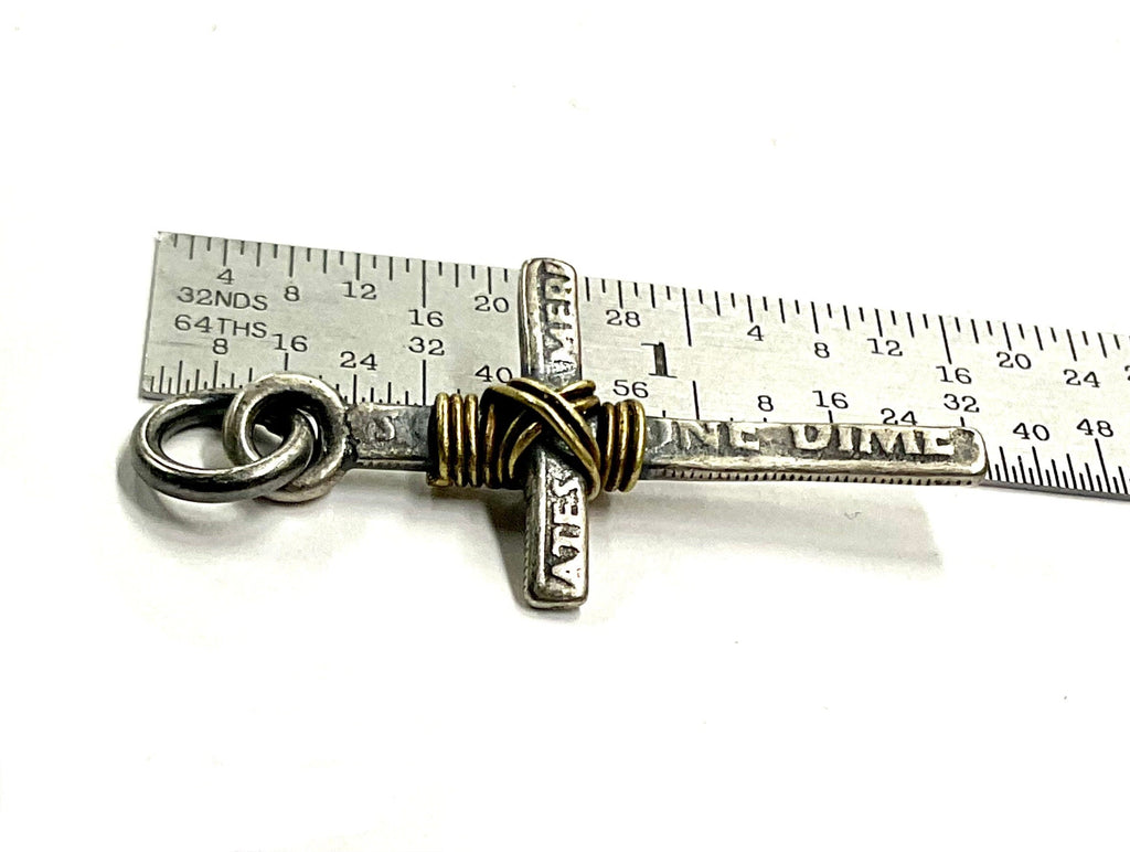 Silver-tone cross necklace pendant with gold wire wrap detail shown with a ruler scale