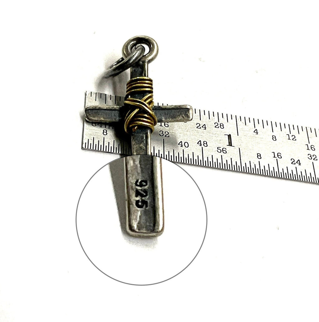 Silver-tone cross pendant bail and gold wire wrap on a measurement ruler background