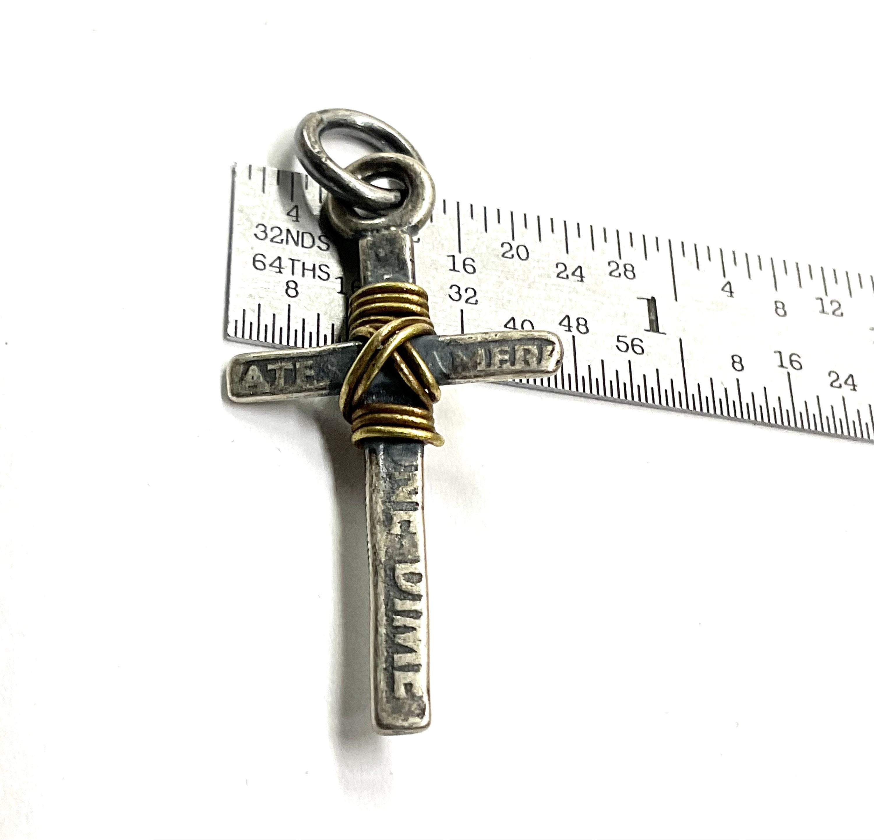 Cross pendant with gold wire wrap and silver-tone bail shown with measurement ruler