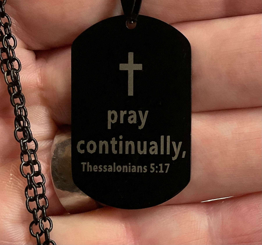 Black dog tag necklace close-up with cross and pray continually Thessalonians 5:17