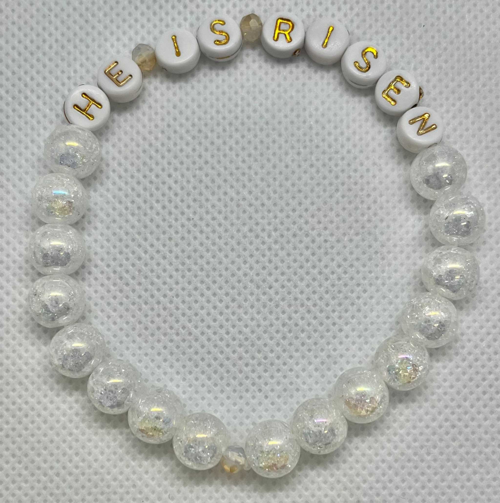 Clear and white beaded bracelet with 'HE IS RISEN' letter beads