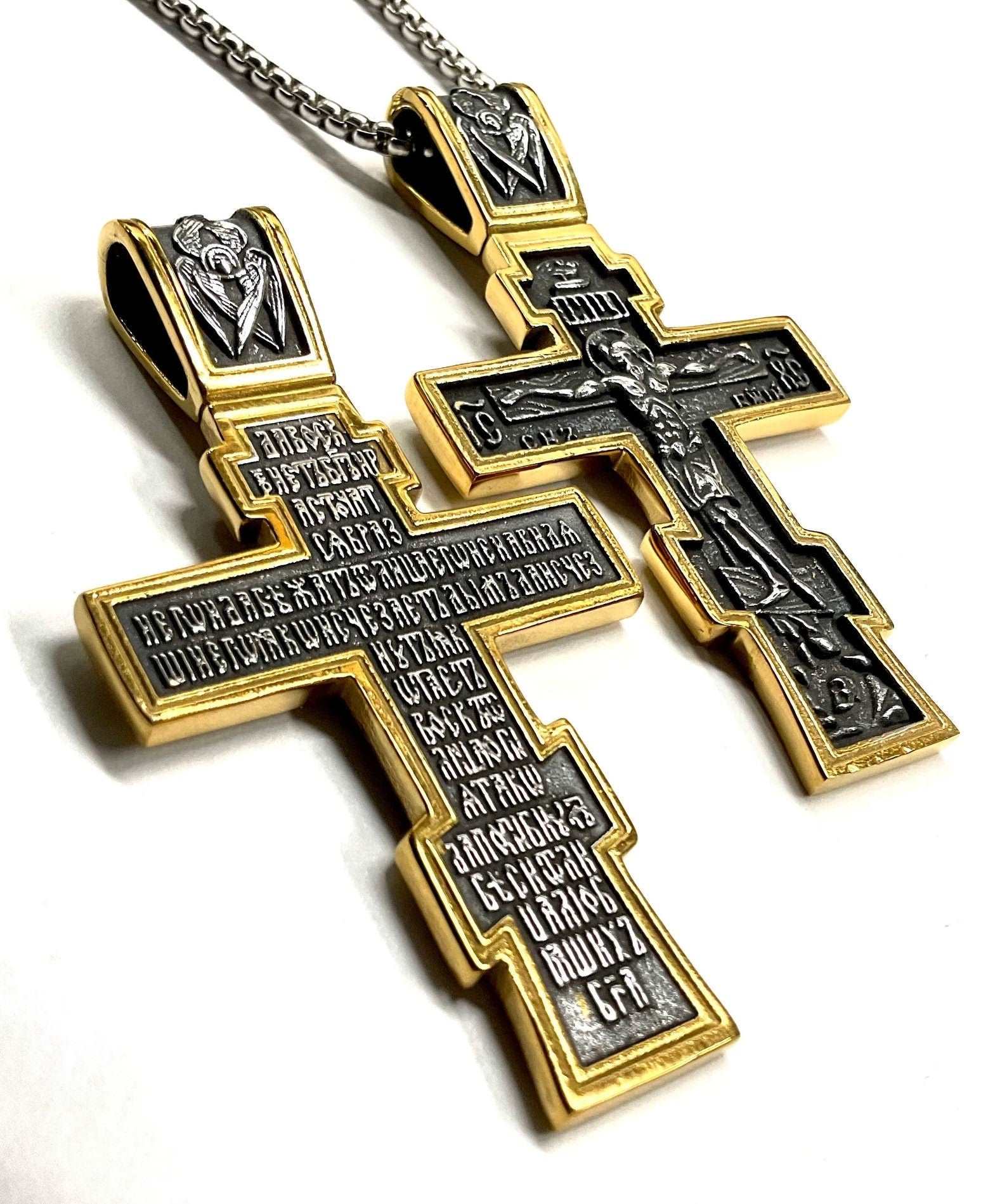 Close-up of gold and silver cross pendant necklace with detailed engravings and chain