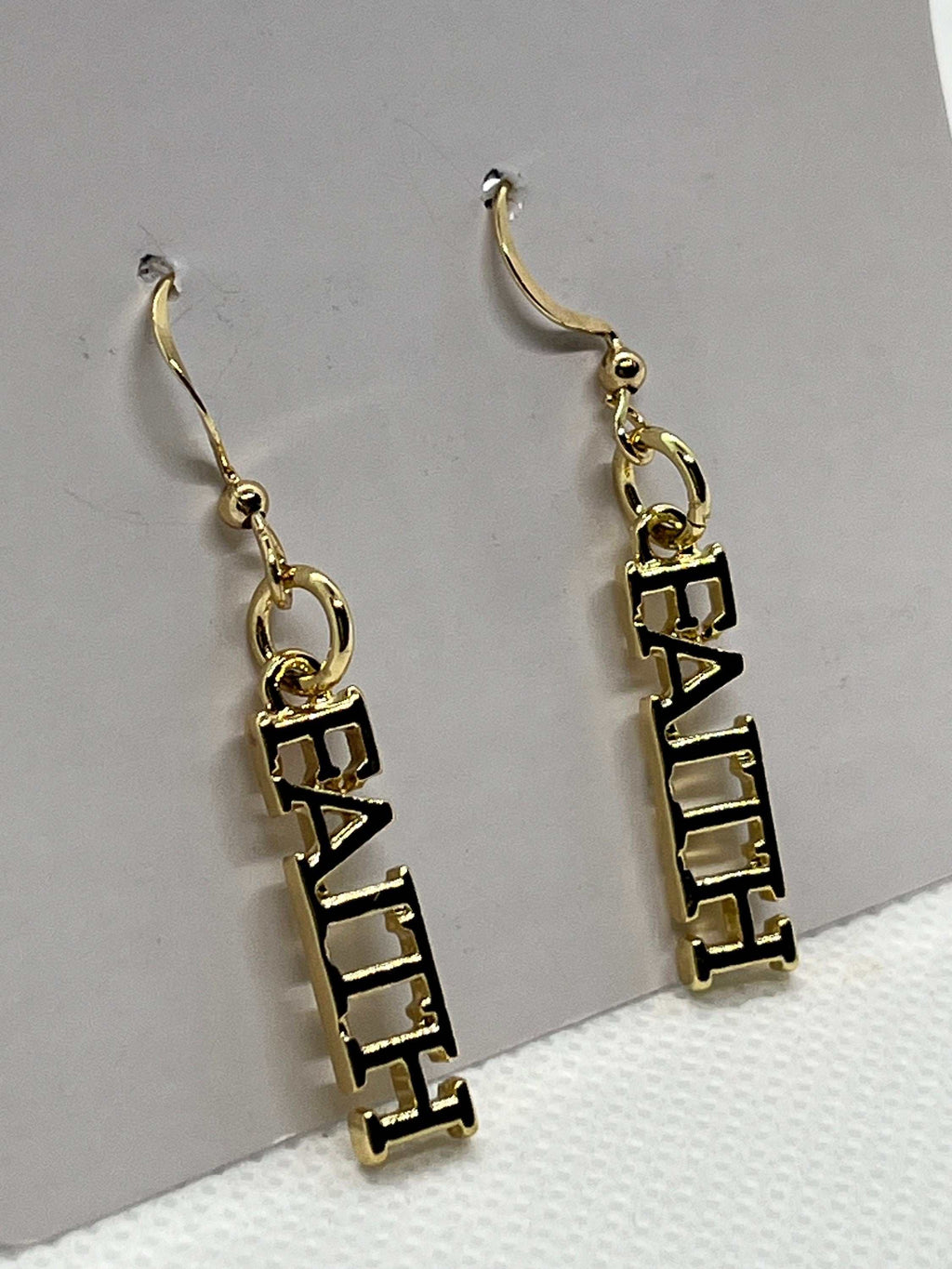 Close-up: 14K gold faith dangle earrings with FAITH block lettering and hooks