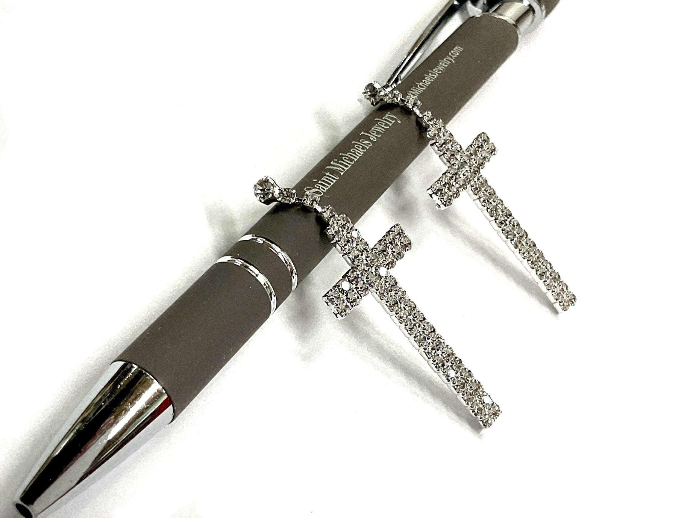Pair of silver-toned crystal cross dangle earrings, with dangling long cross shapes.
