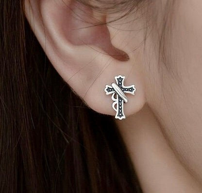 Sterling silver cross stud earring with blue enamel on a wearer's ear