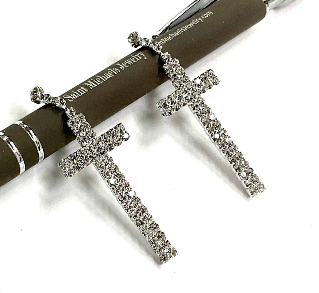 Sparkly crystal cross dangle earrings with small top charms, silver-toned.
