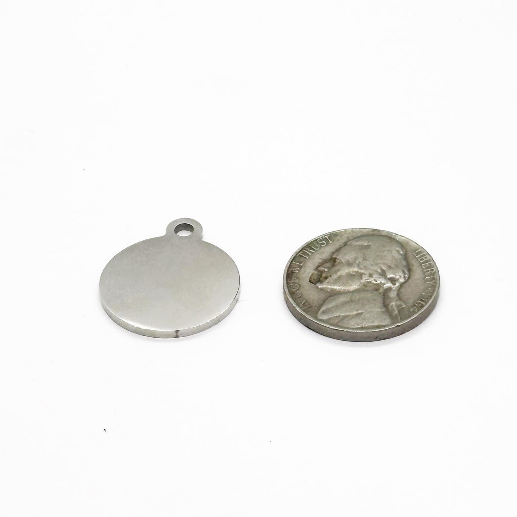 Round silver charm with top hole, shown beside a coin for size