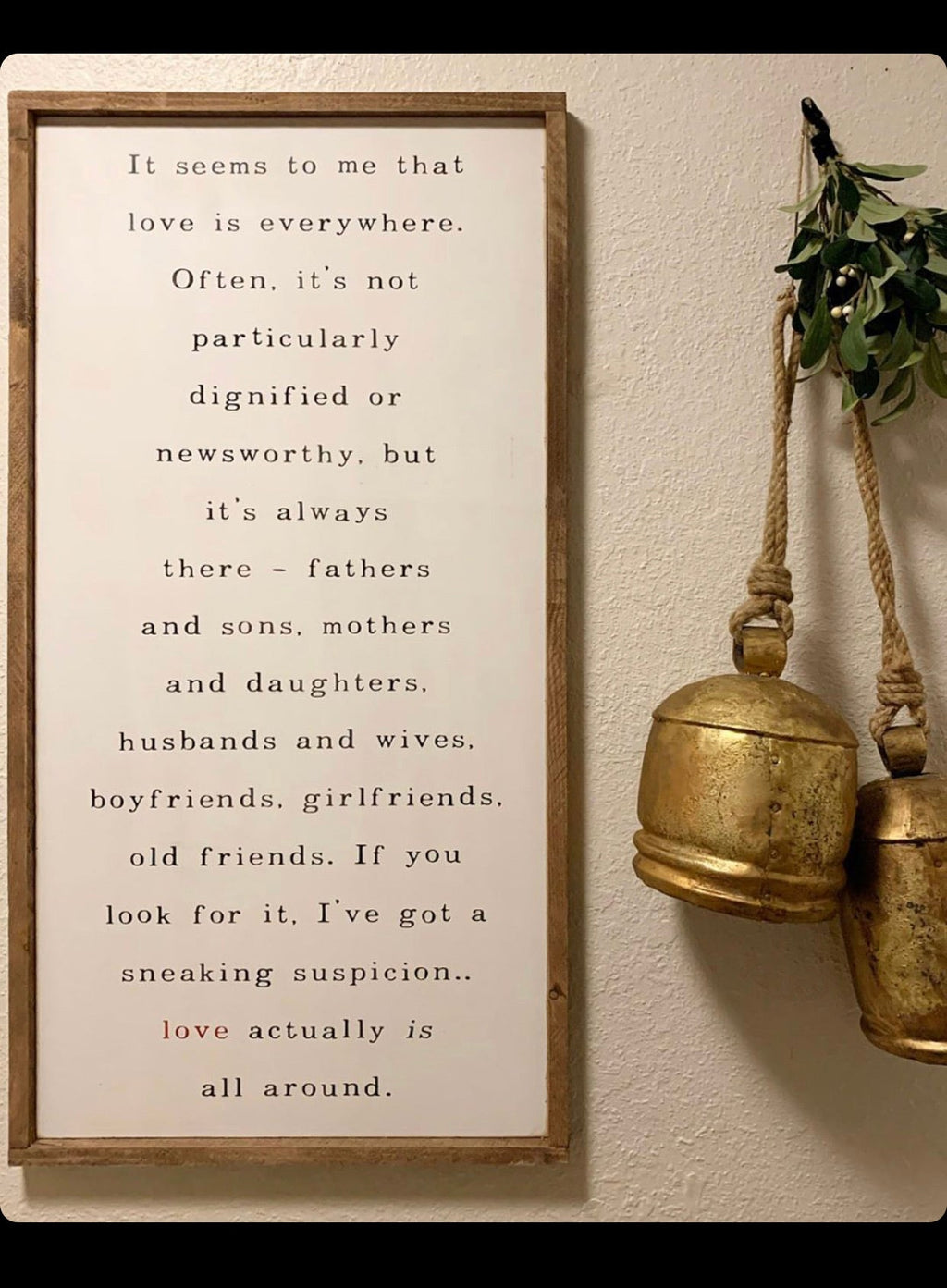 Framed wall hanging with wooden frame, vertical quote text, and brass bell ornament