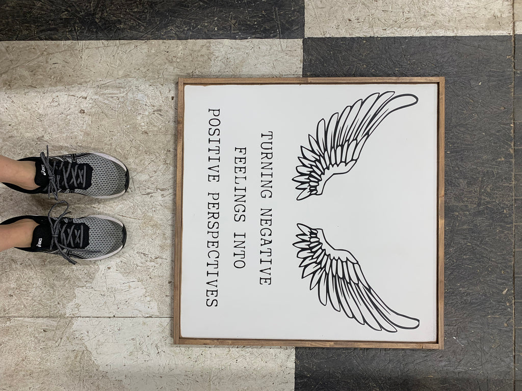 Framed wood sign with black wing icon and text: Turning negative feelings to positive