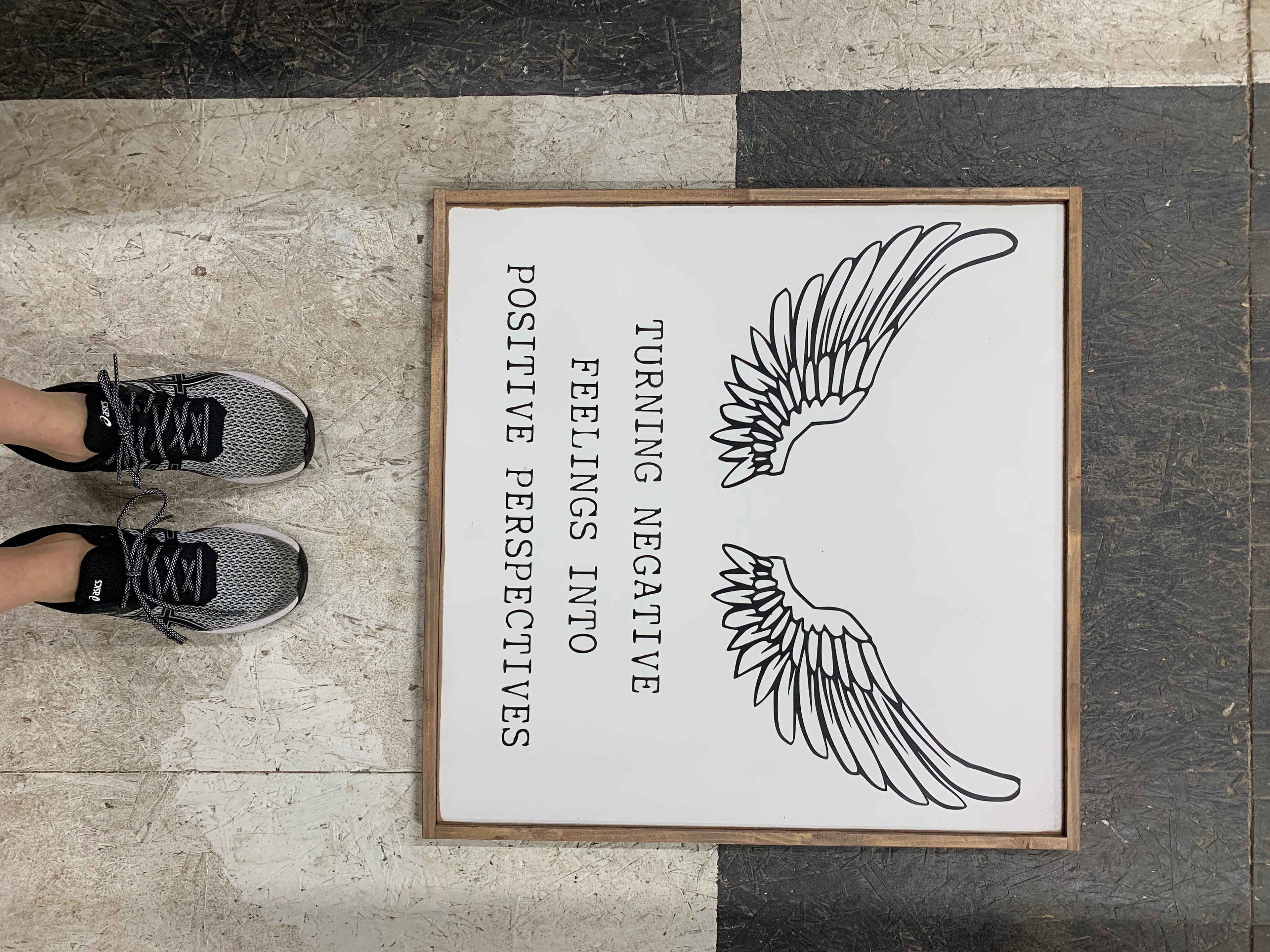 Framed wood sign with black wing icon and text: Turning negative feelings to positive