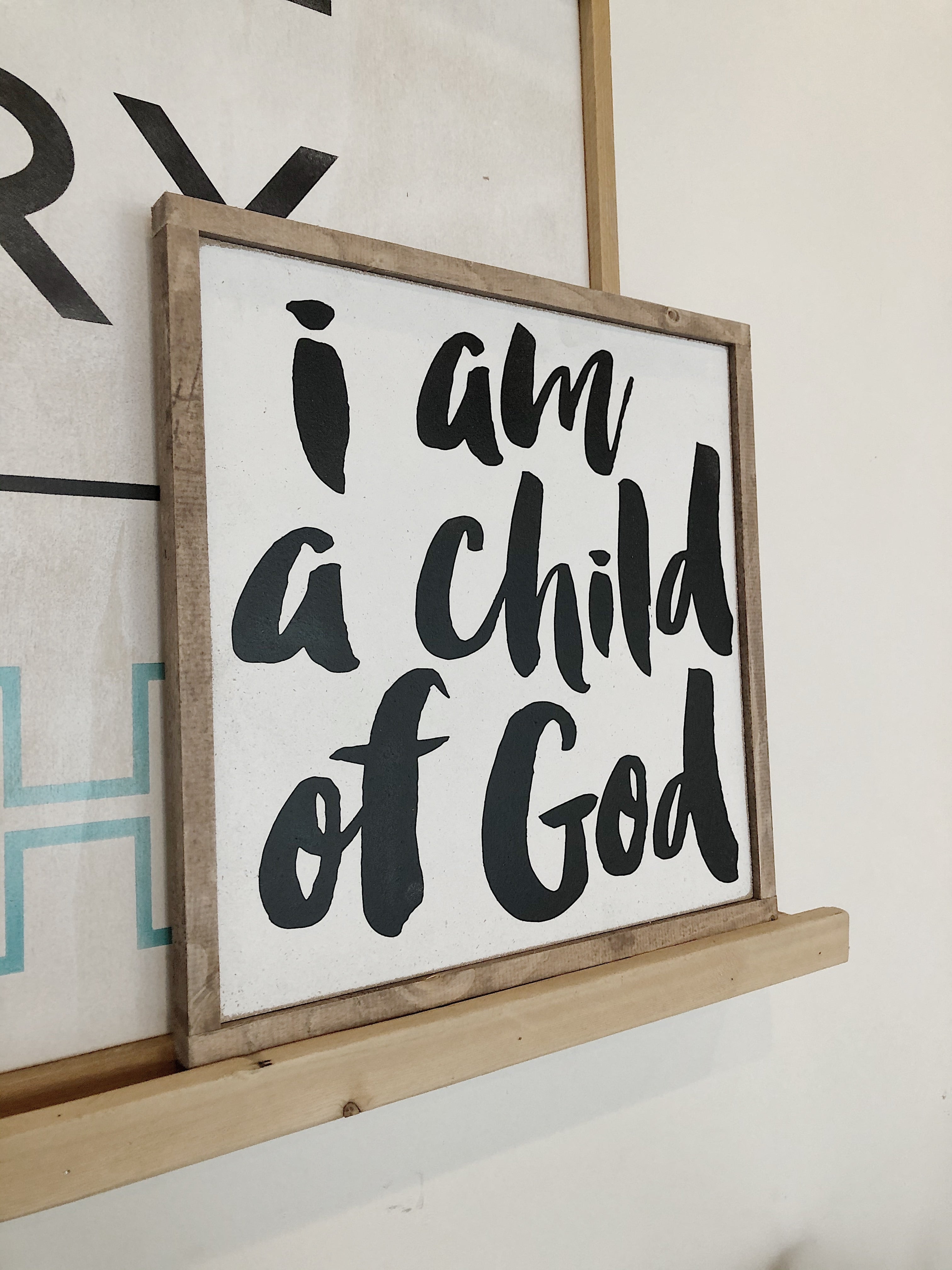 Framed wall art sign with black script text: “I am a child of God”