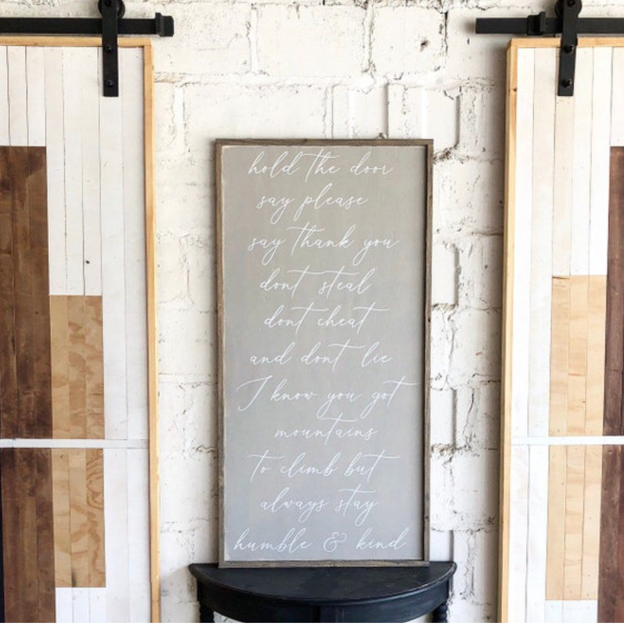 Wood wall sign with light cursive inspirational quote on dark background