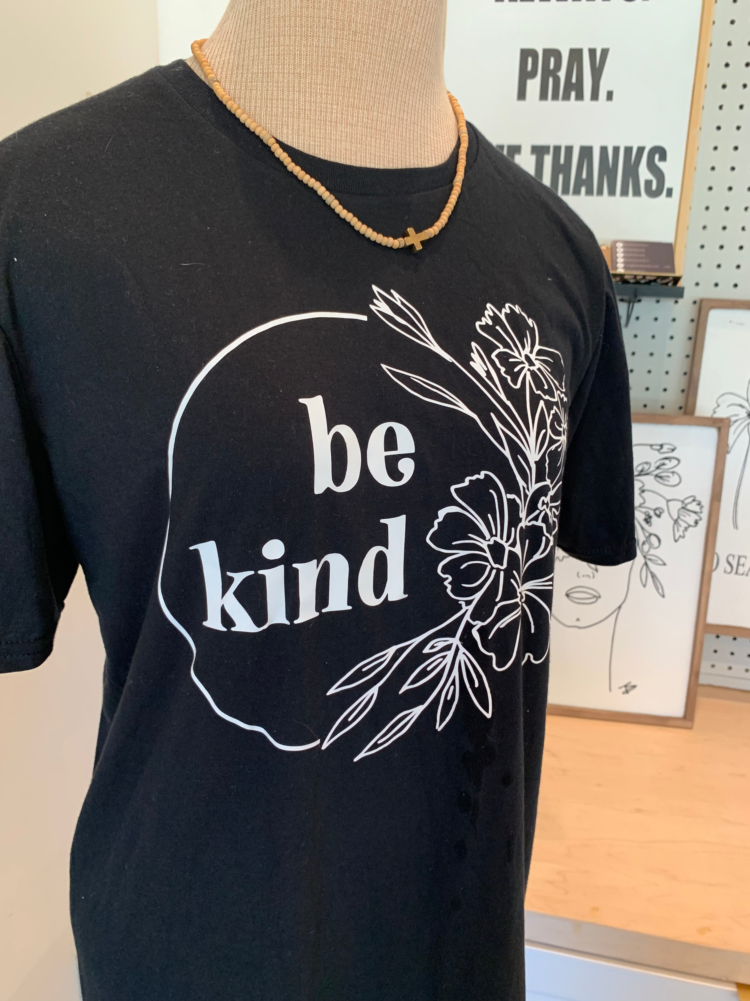 Black T-shirt with white 'be kind' circular floral lettering graphic