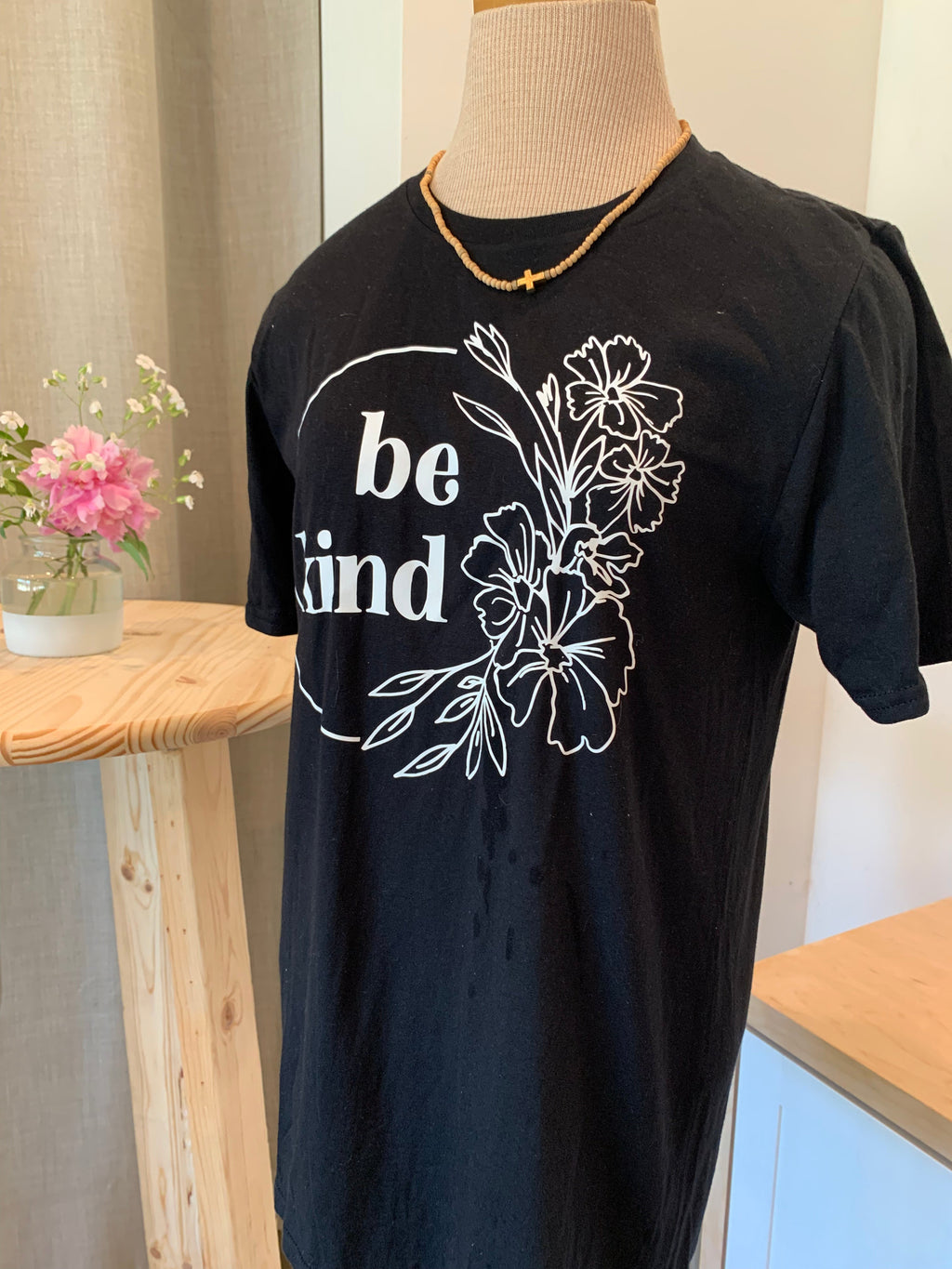 Black T-shirt with white 'be kind' floral branch and bloom graphic