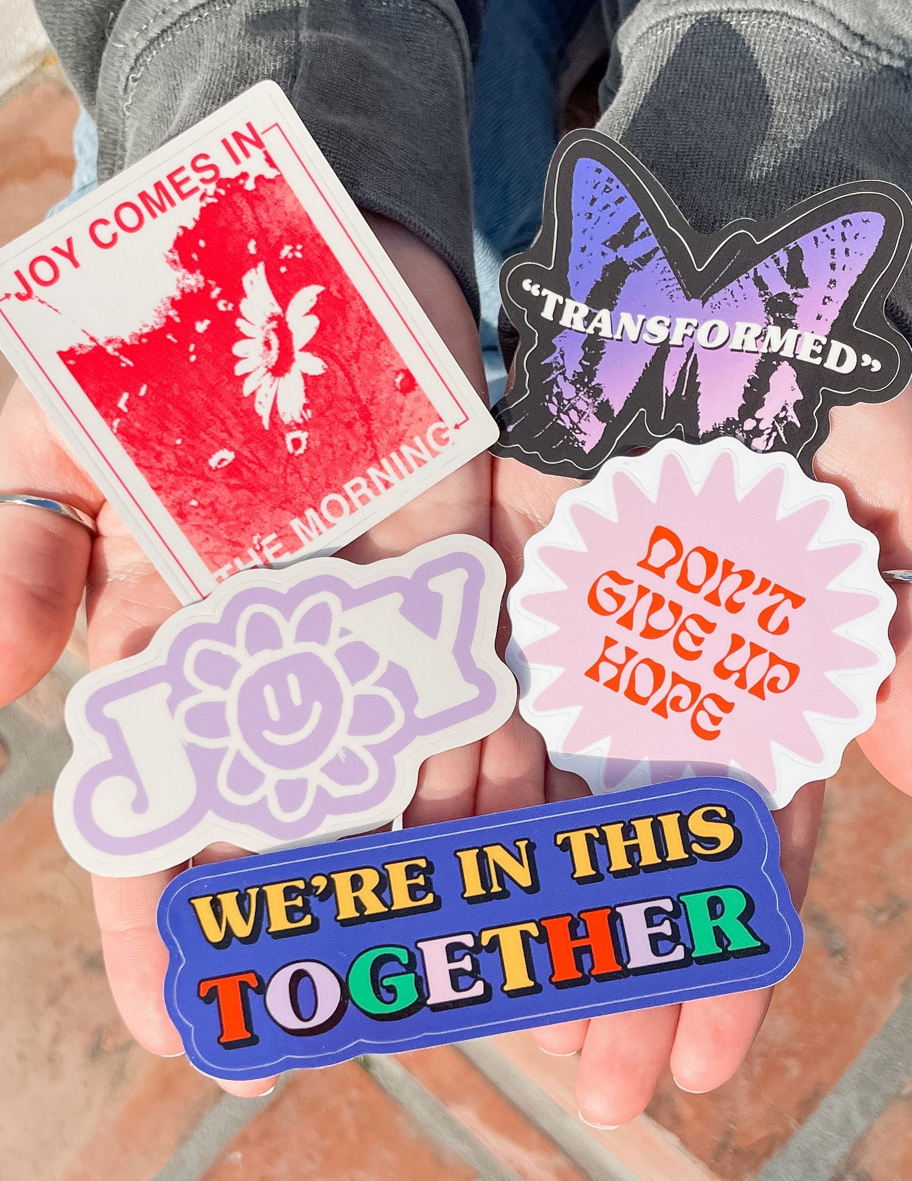 Sticker pack with purple 'Transformed' bat, light purple flowers, and blue together banner