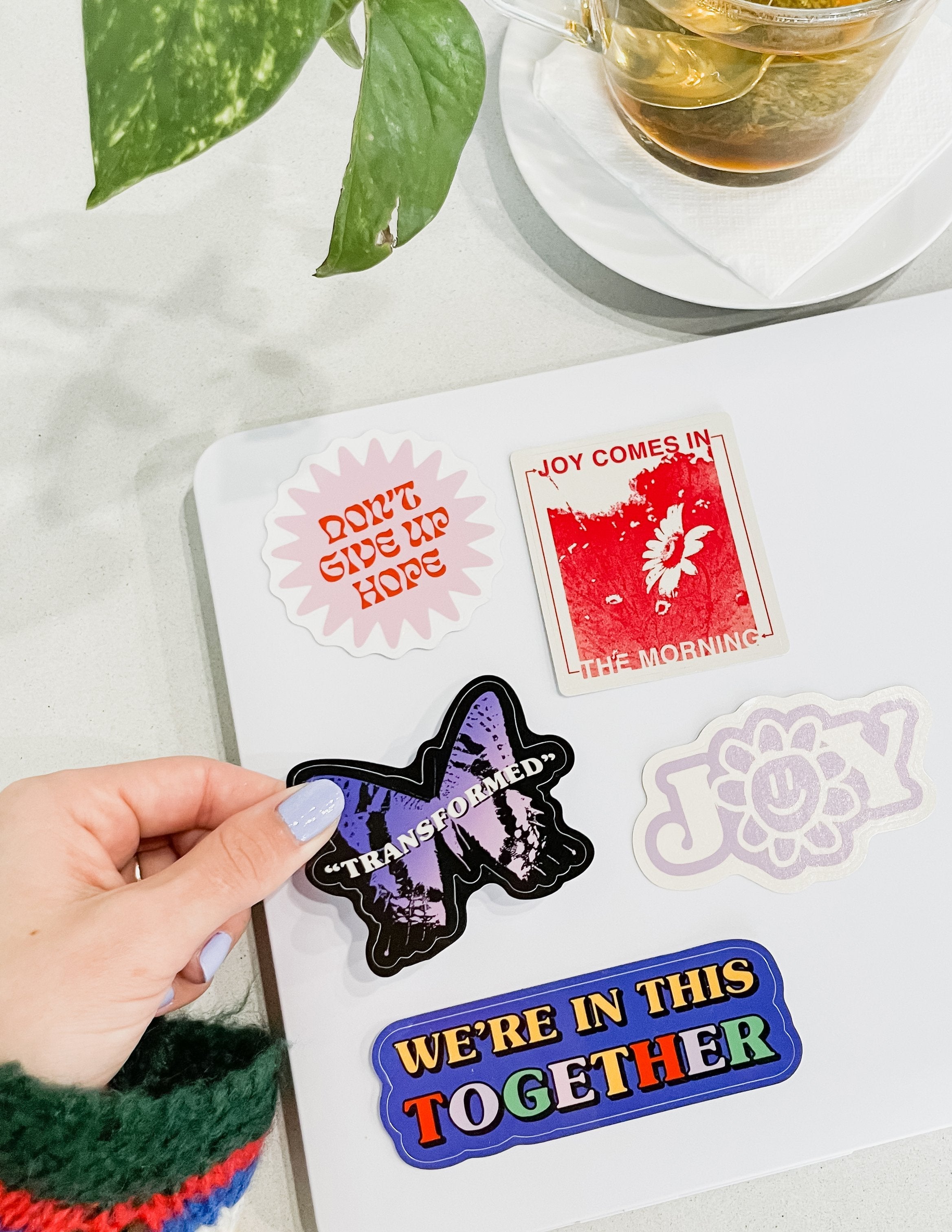 Sticker pack with red 'Joy comes in' card, 'Transformed' bat, and flower decals