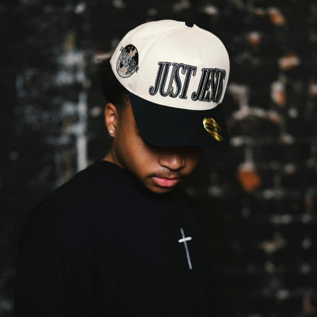 Cream and black snapback cap with embroidered "JUST JESUS" logo on front.