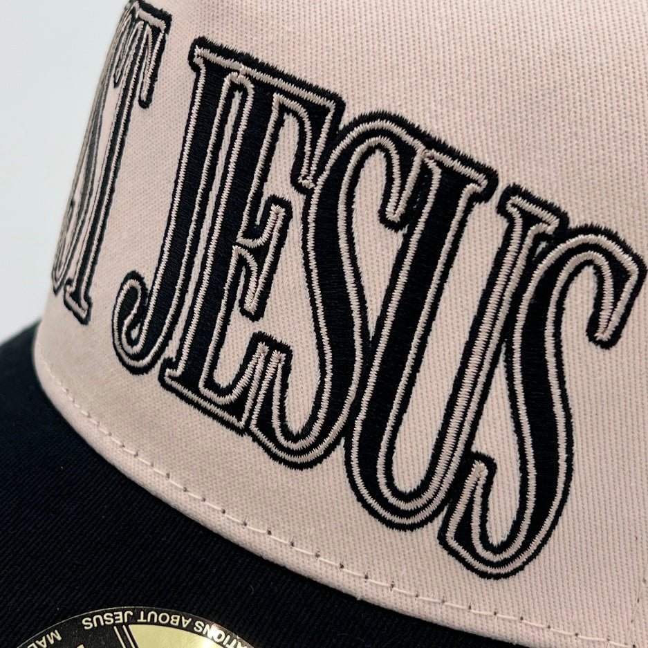 Cream snapback cap with black embroidered "JUST JESUS" front panel.