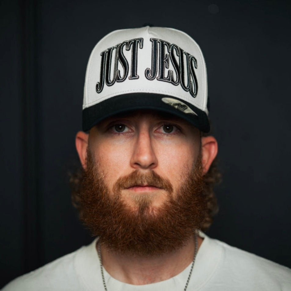 Cream and black snapback cap with large embroidered "JUST JESUS" on front.
