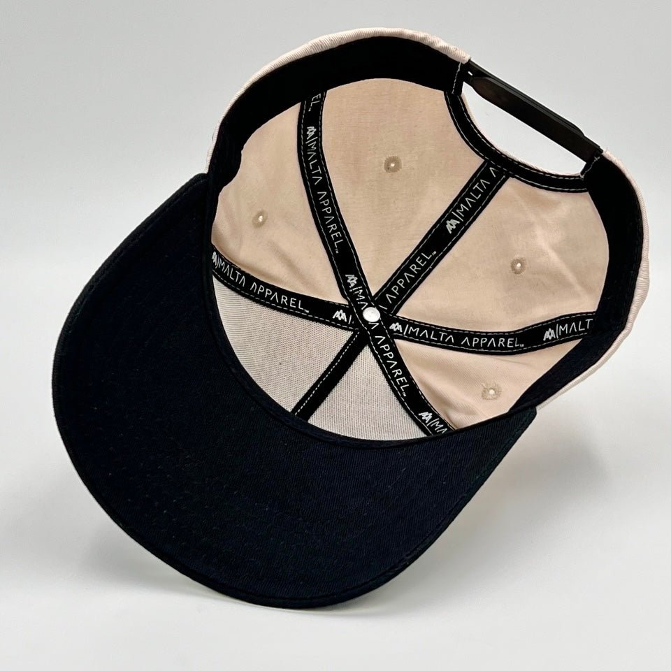 Cream cap interior with black woven "AMALT Apparel" straps and buttons.