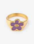Gold-tone ring with lavender flower face, smiling center, enamel detail