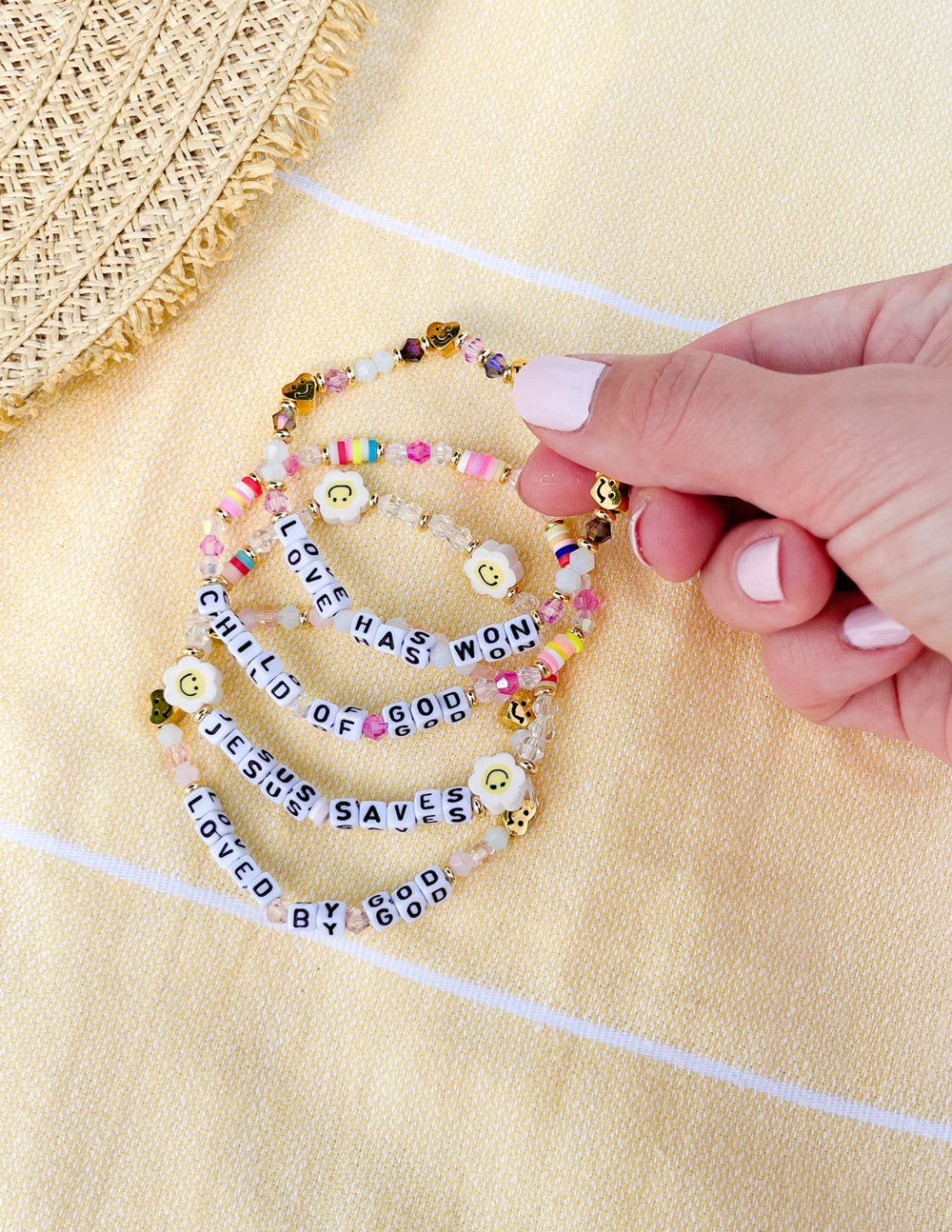 Colorful letter bracelet close-up with round beads, smiley charms, and gold links