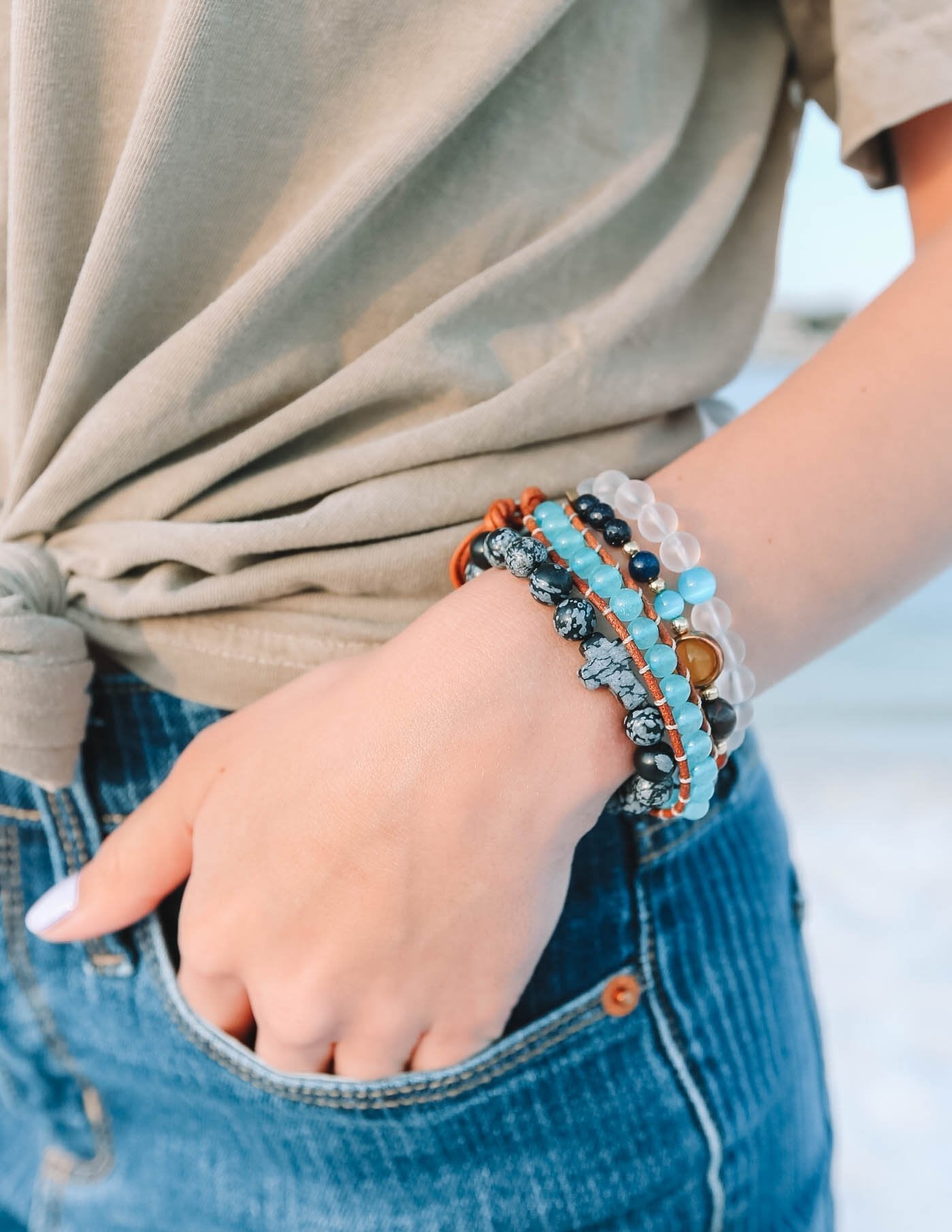 Stacked beaded bracelets on wrist with dark, blue, and orange stone beads