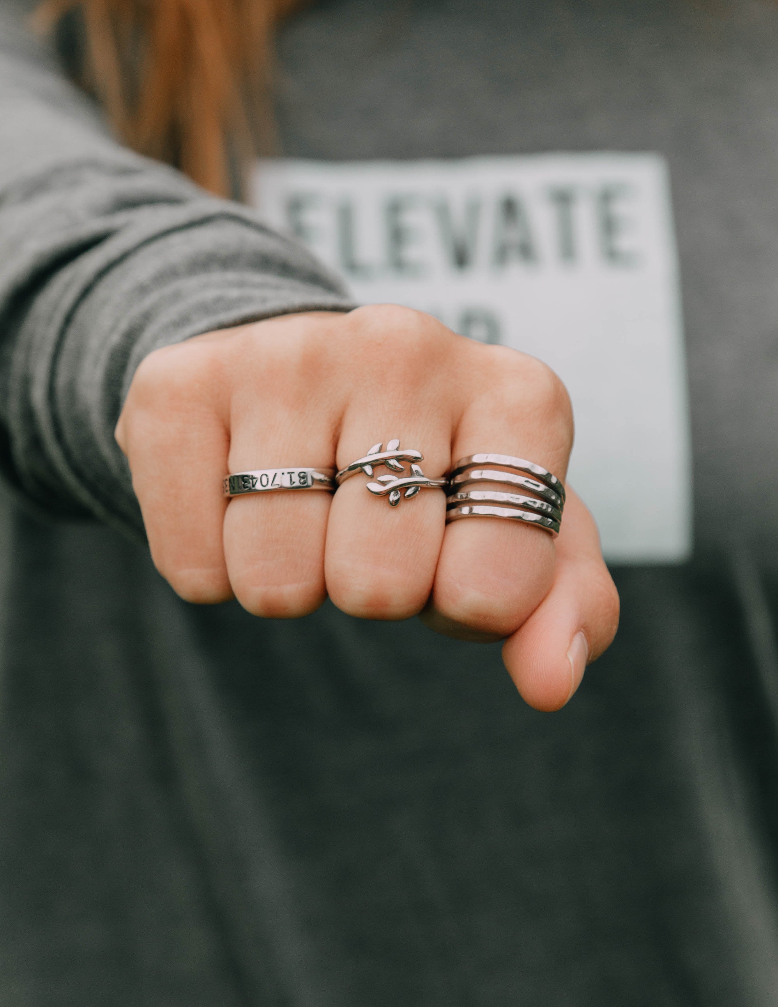 Silver olive branch ring with leaf motif among stacked rings