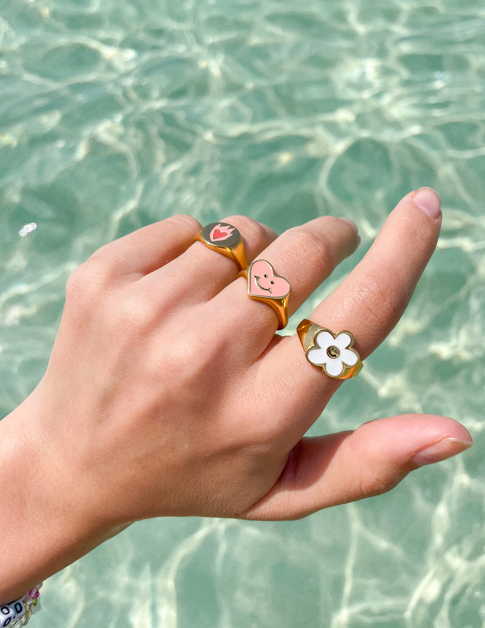 Gold-tone smiley heart enamel ring on hand, pink heart with wink and smile