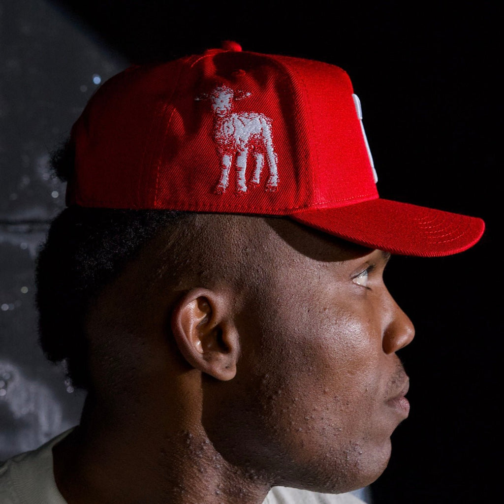 Red snapback cap worn in profile with white animal graphic on front