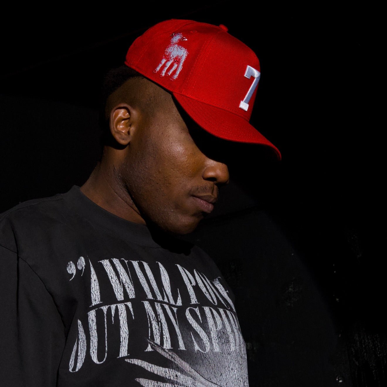 Red snapback cap worn by model, showing white '7' front logo