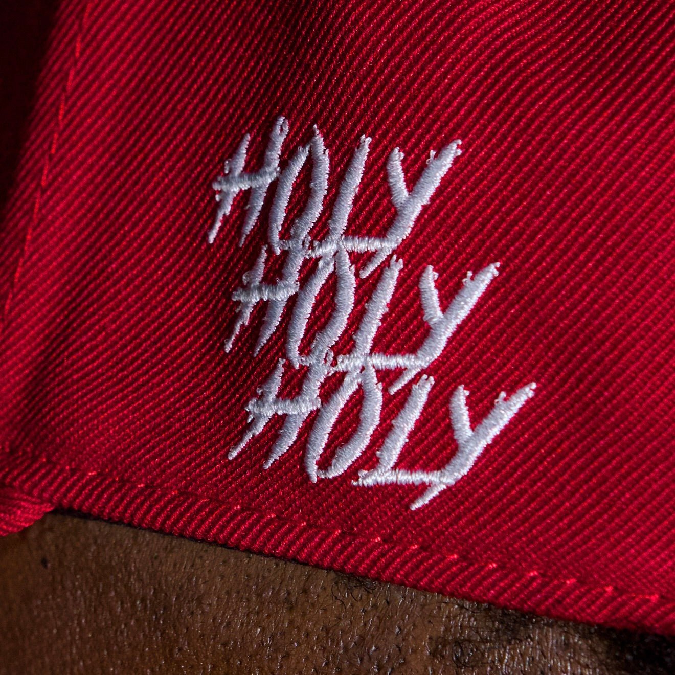 Red cap fabric close-up with white script logo on front