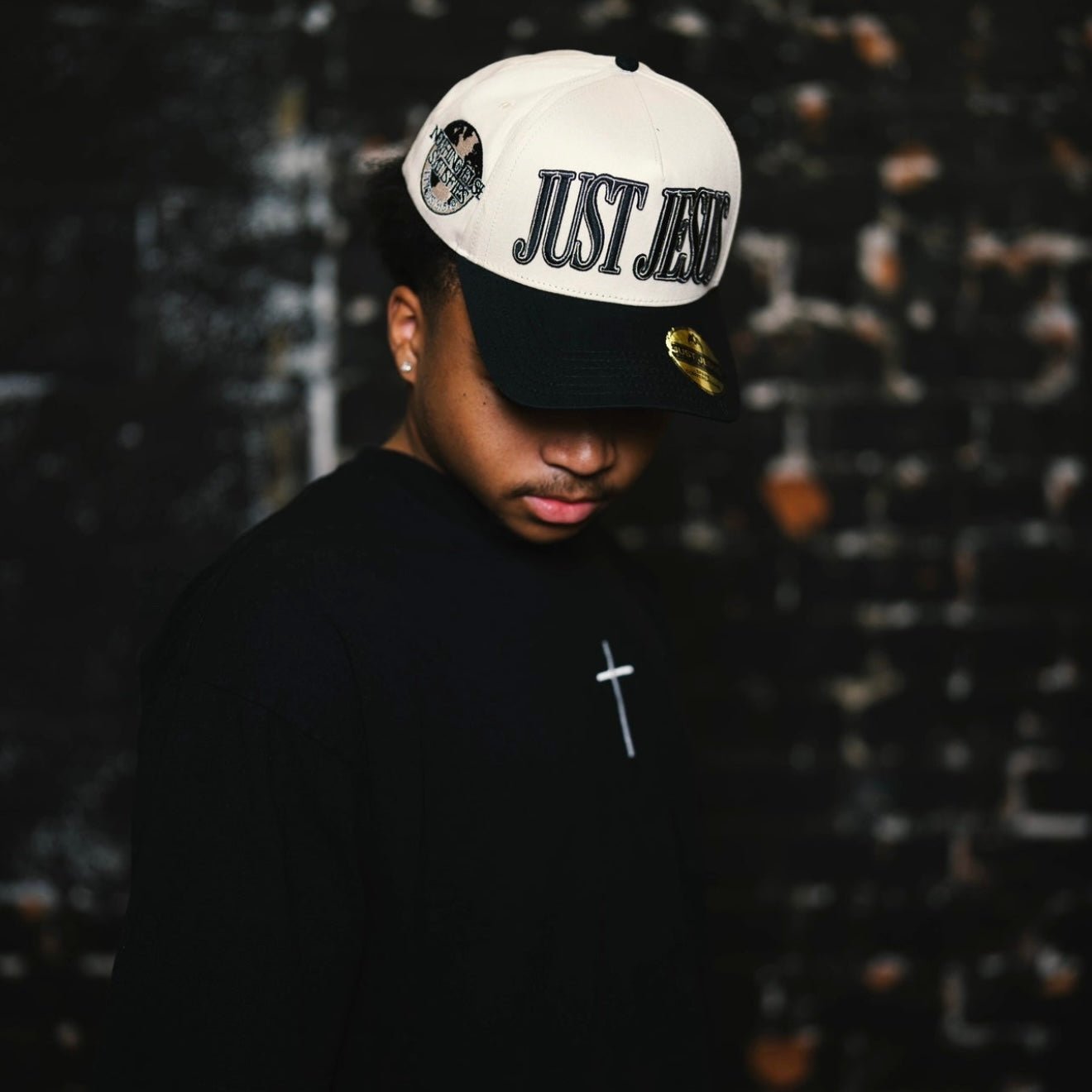 Black T-shirt with small white cross on the chest.