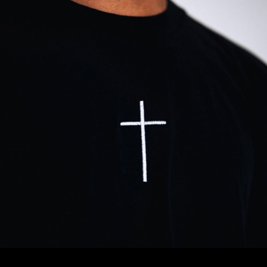 Close-up of small white cross on a black T-shirt.