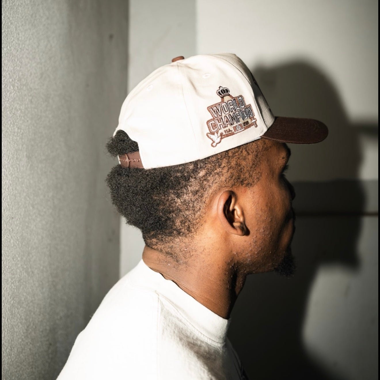 Cream snapback cap with World Champion side patch and brown brim
