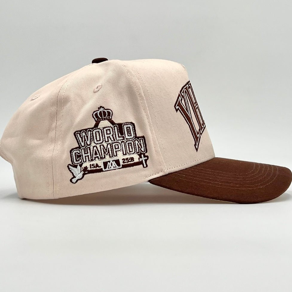 Cream snapback cap with World Champion patch and side YHWH logo, brown brim