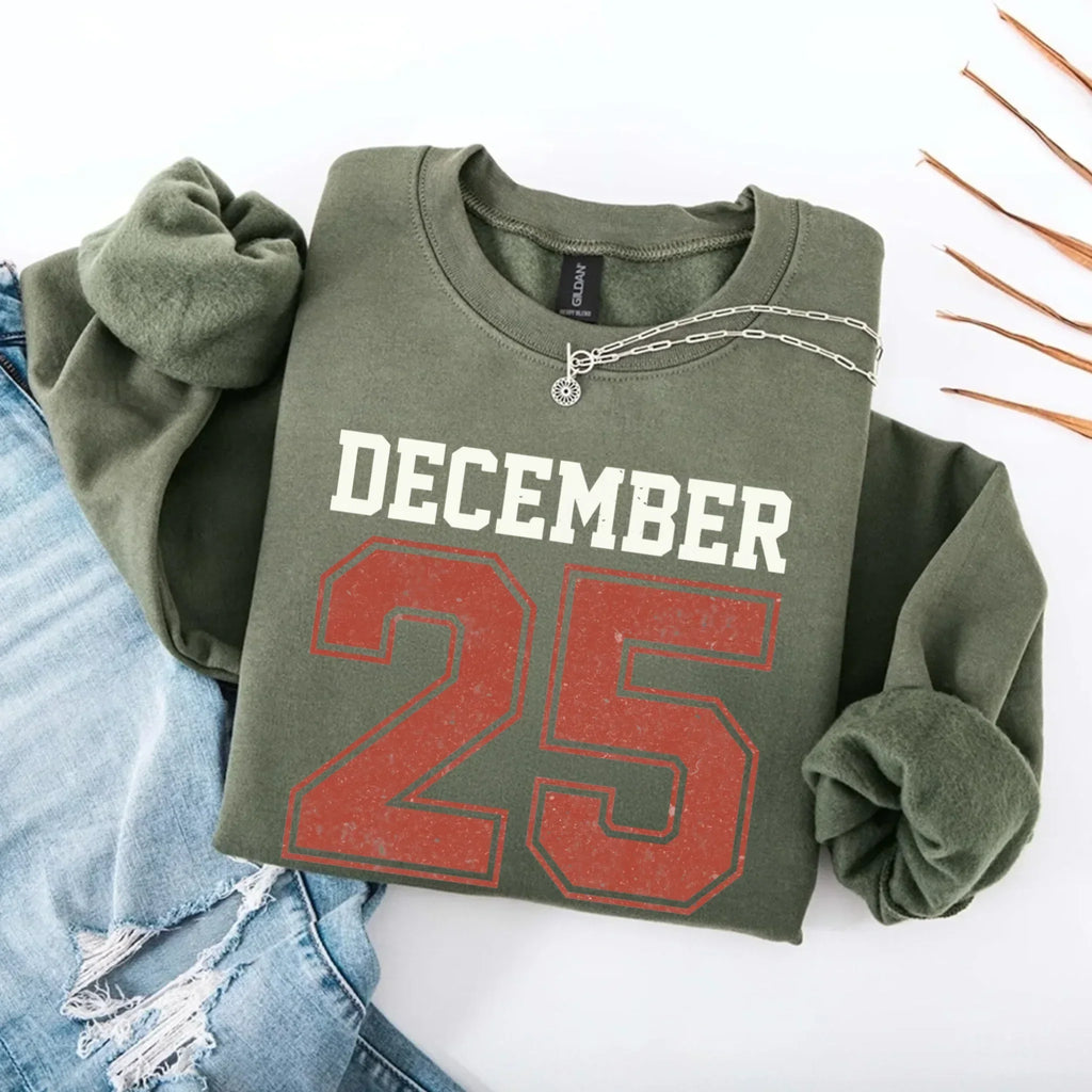 Olive green crewneck sweatshirt with “DECEMBER 25” graphic and silver chain detail.
