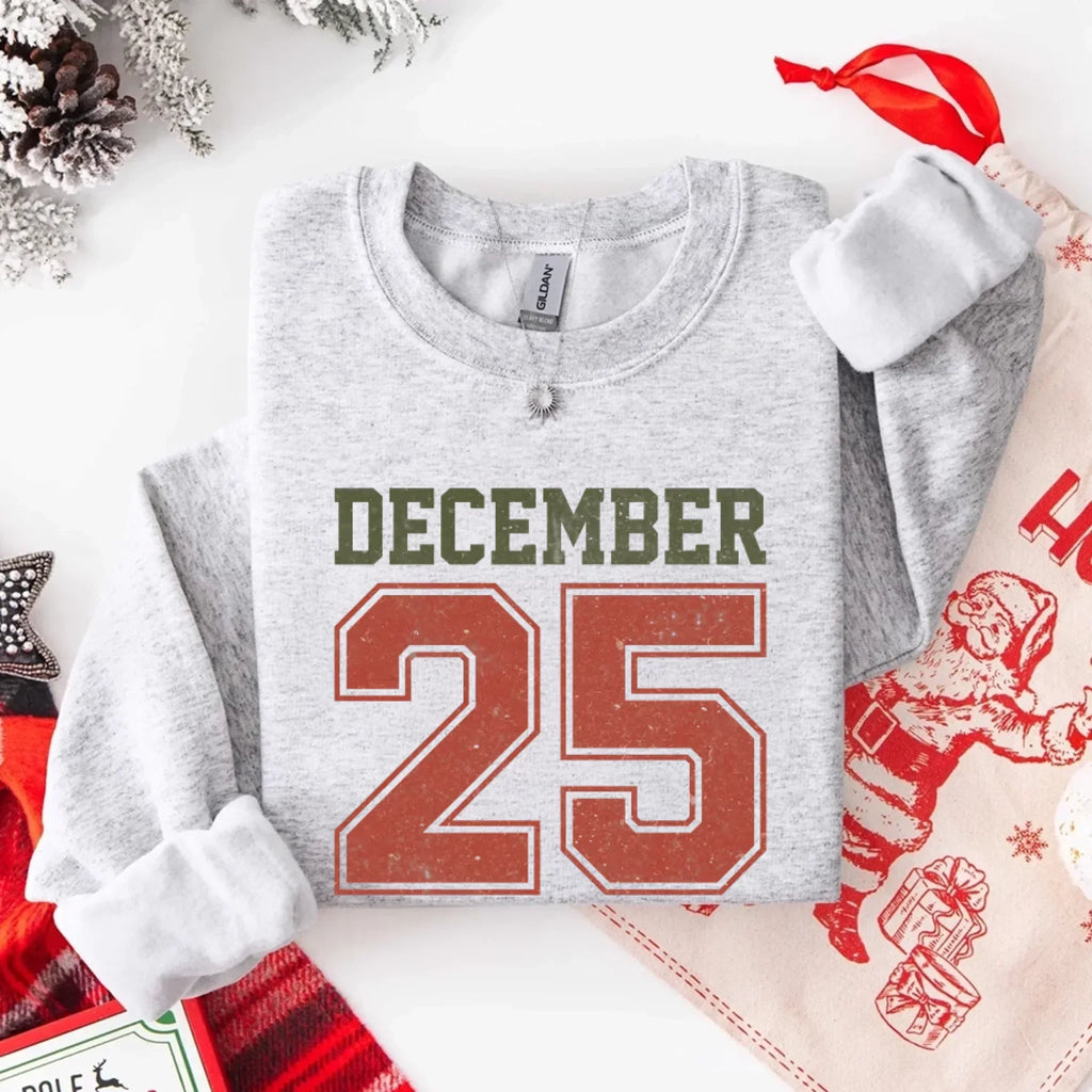 Heather gray crewneck sweatshirt with “DECEMBER 25” graphic and silver chain detail.