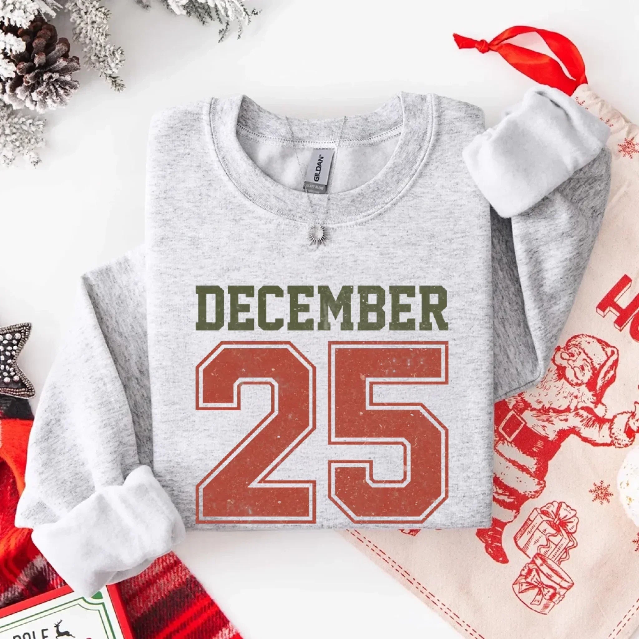 Heather gray crewneck sweatshirt with “DECEMBER 25” graphic and silver chain detail.