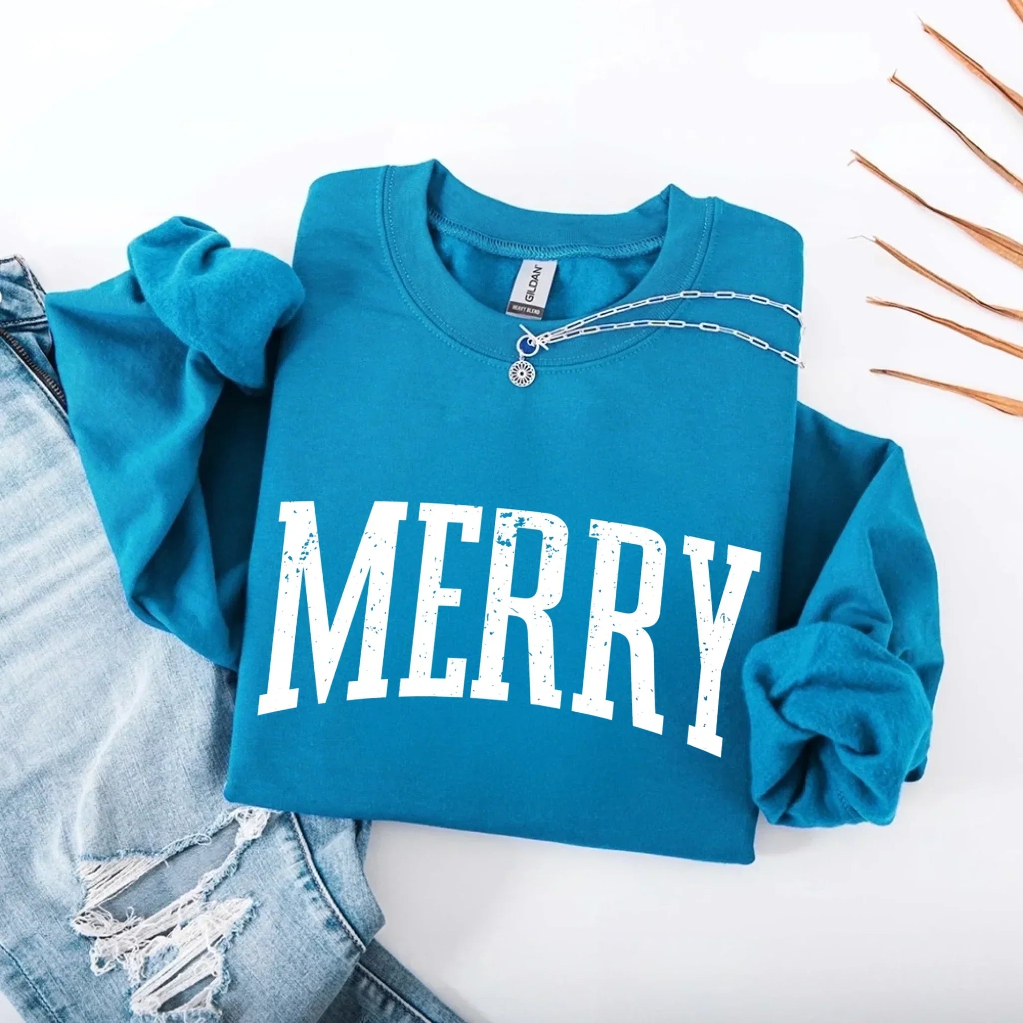 Women’s holiday sweatshirt in teal with “MERRY” front graphic and crewneck buttons