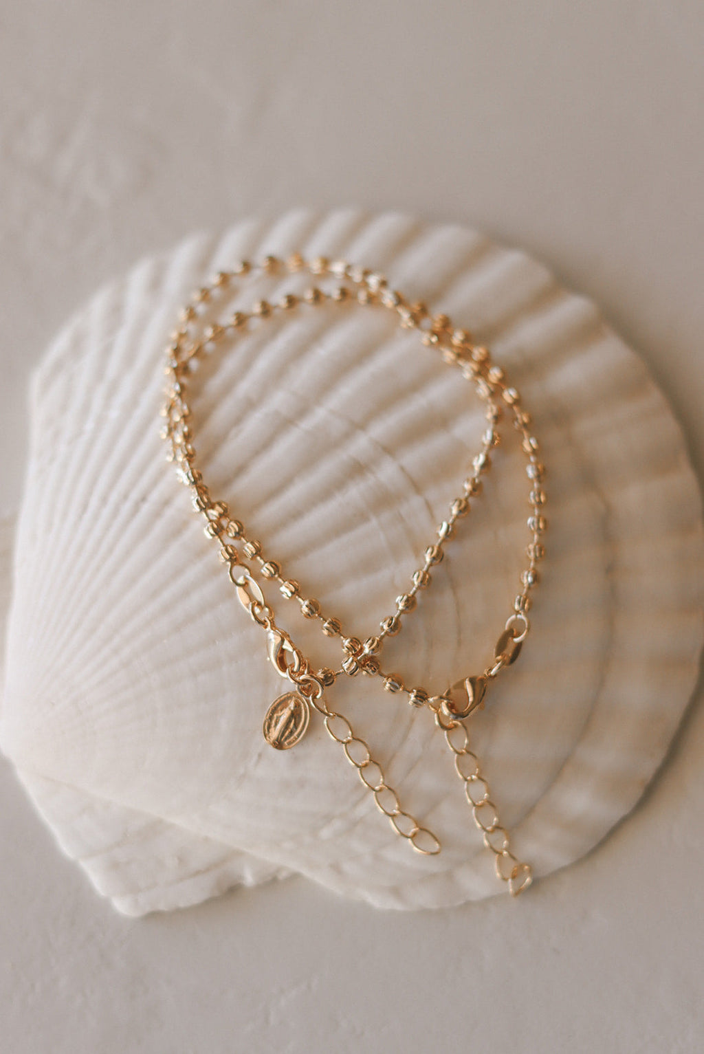 Gold-tone medal charm bracelet with beaded chain and dangling oval pendant