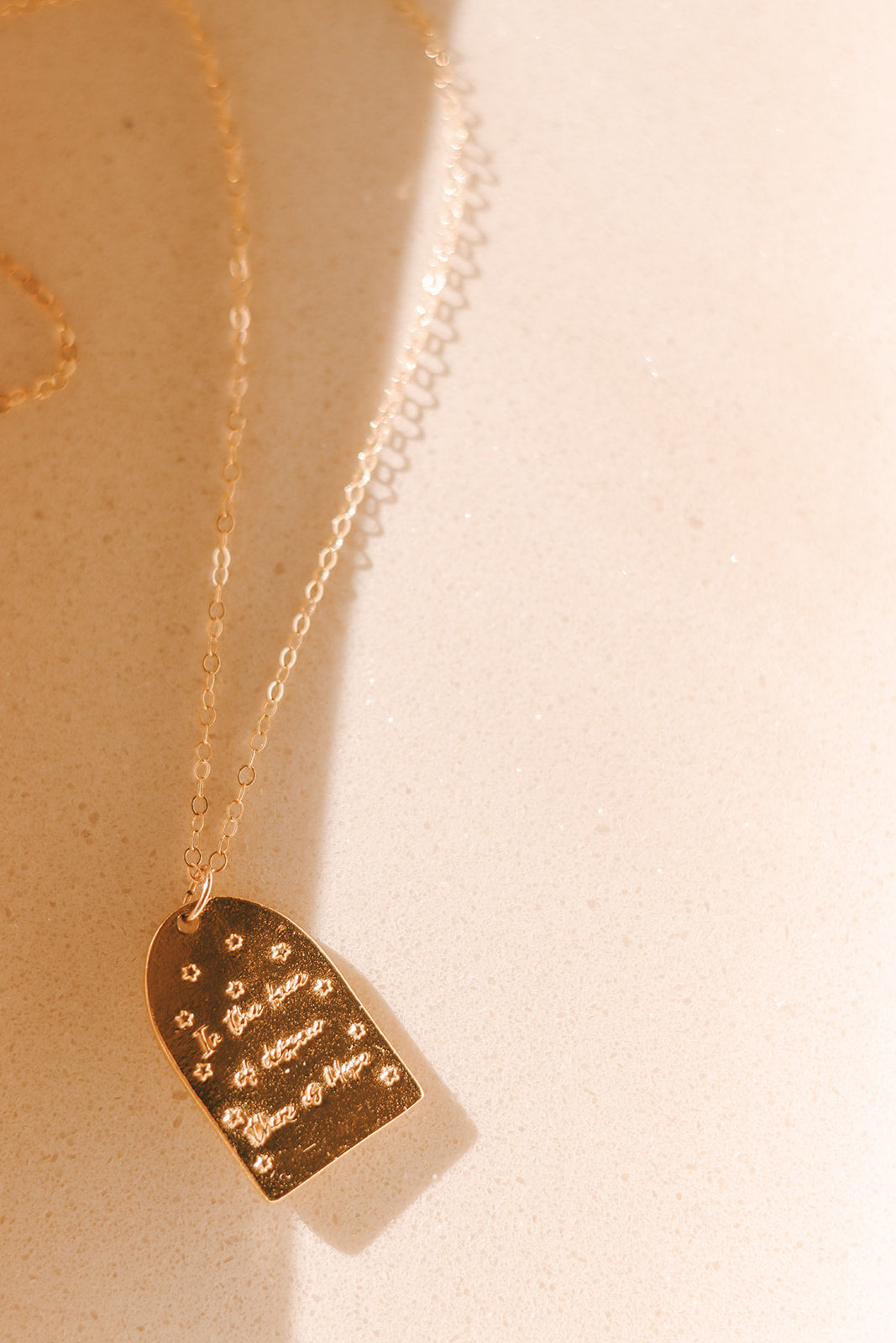 Gold-tone pendant necklace with small plaque charm and engraved text