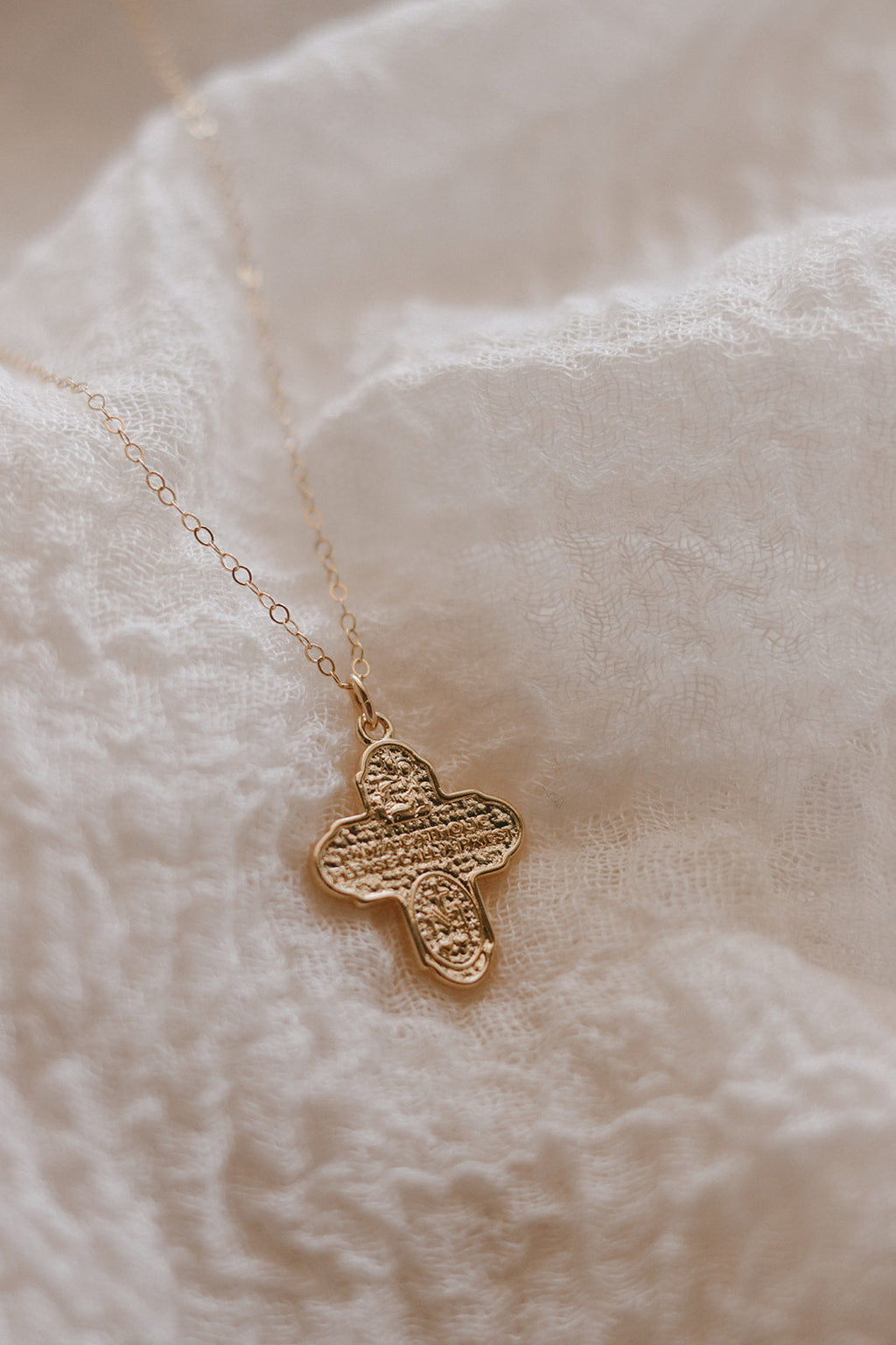 Gold cross necklace with textured cross pendant on a delicate chain