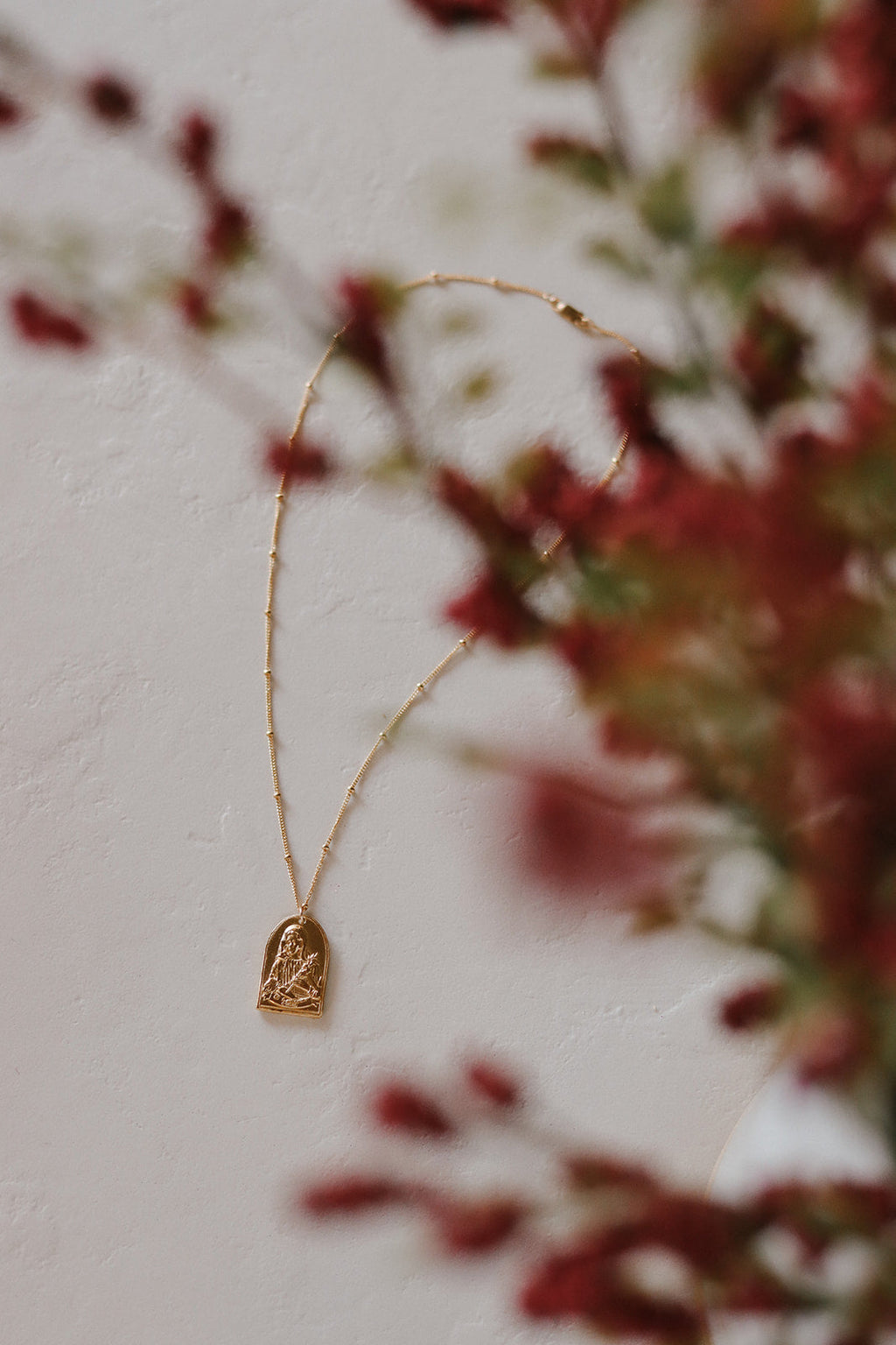 Gold-tone St. Catherine pendant necklace with small arch charm on thin chain.