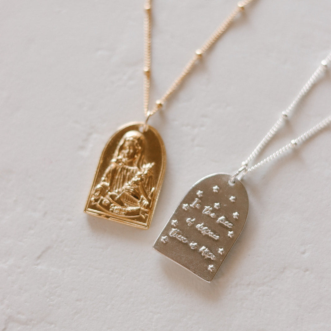 Two pendant necklaces with gold and silver-tone arched charms on chains