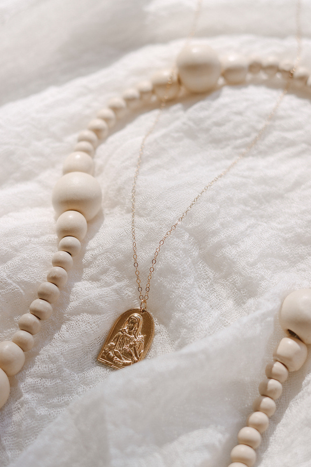 Gold-tone arched Saint pendant necklace with chain and white bead strand