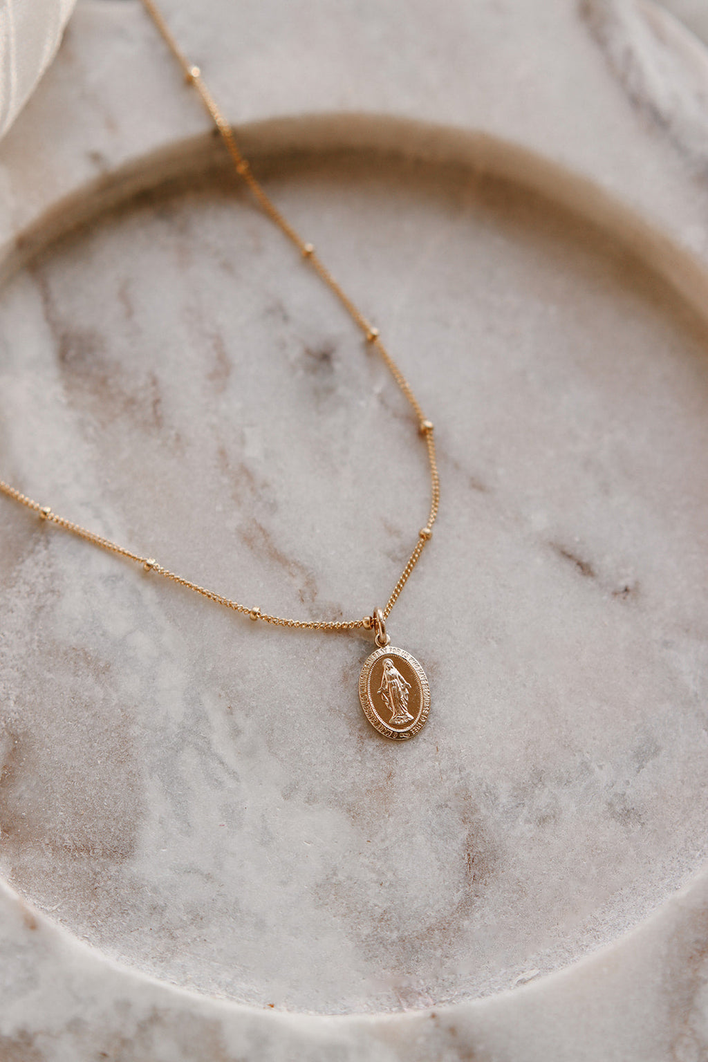 Gold chain necklace with small oval medal pendant at the center