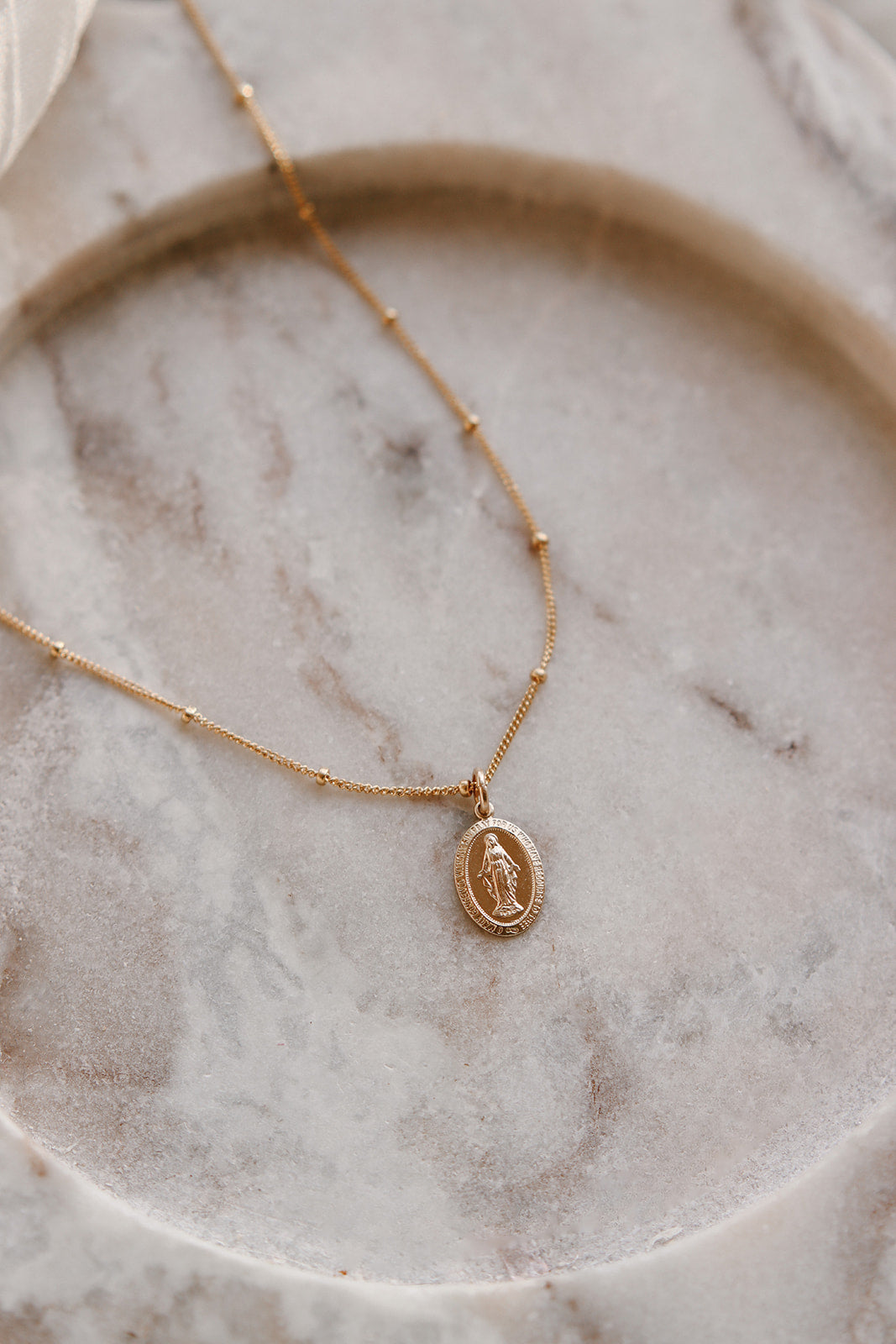 Gold chain necklace with small oval medal pendant at the center