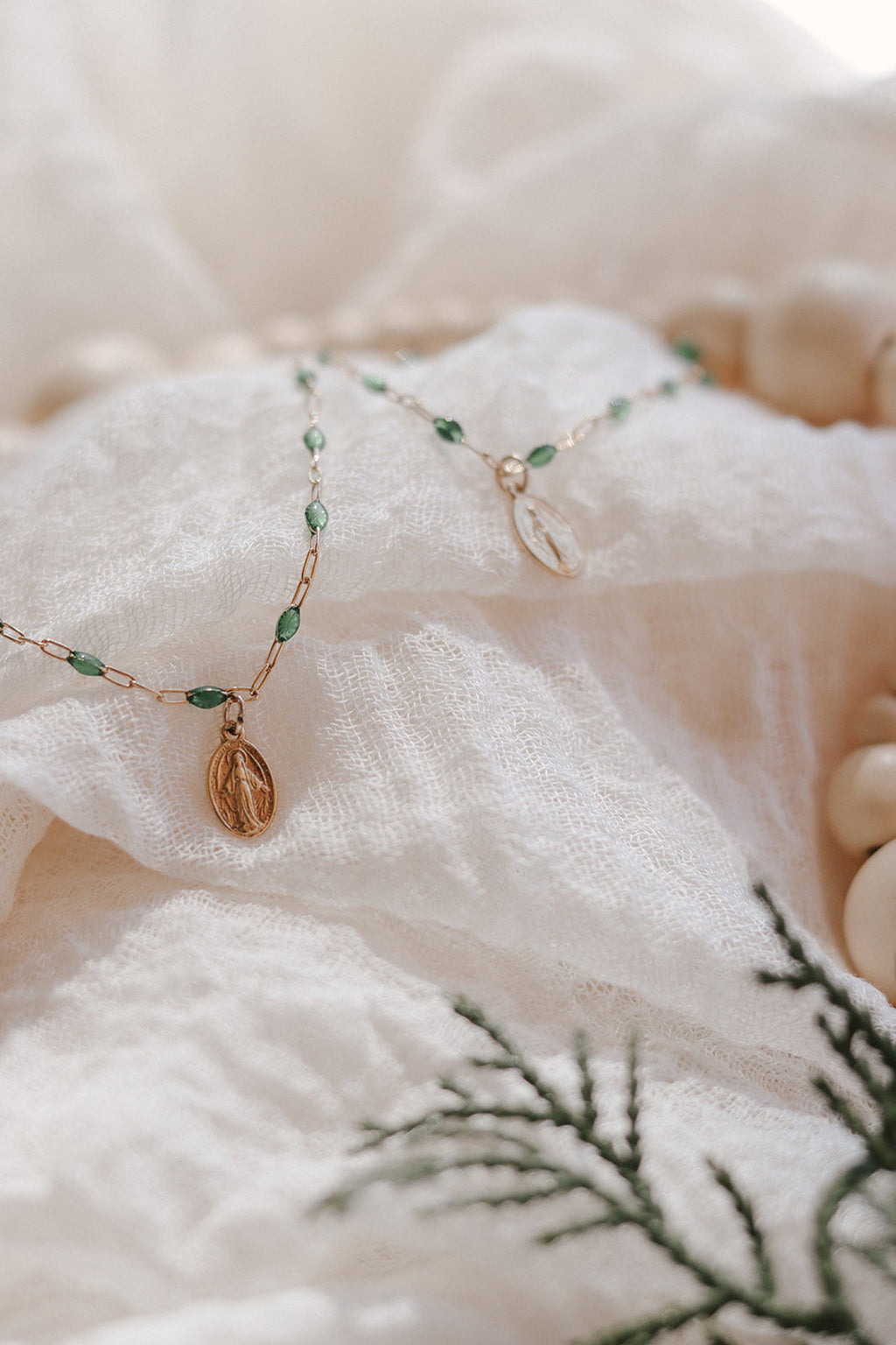 Green beaded bracelet with oval medal charm and gold links, close view